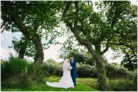 Bride and groom under trees at Oldwalls Gower wedding venue